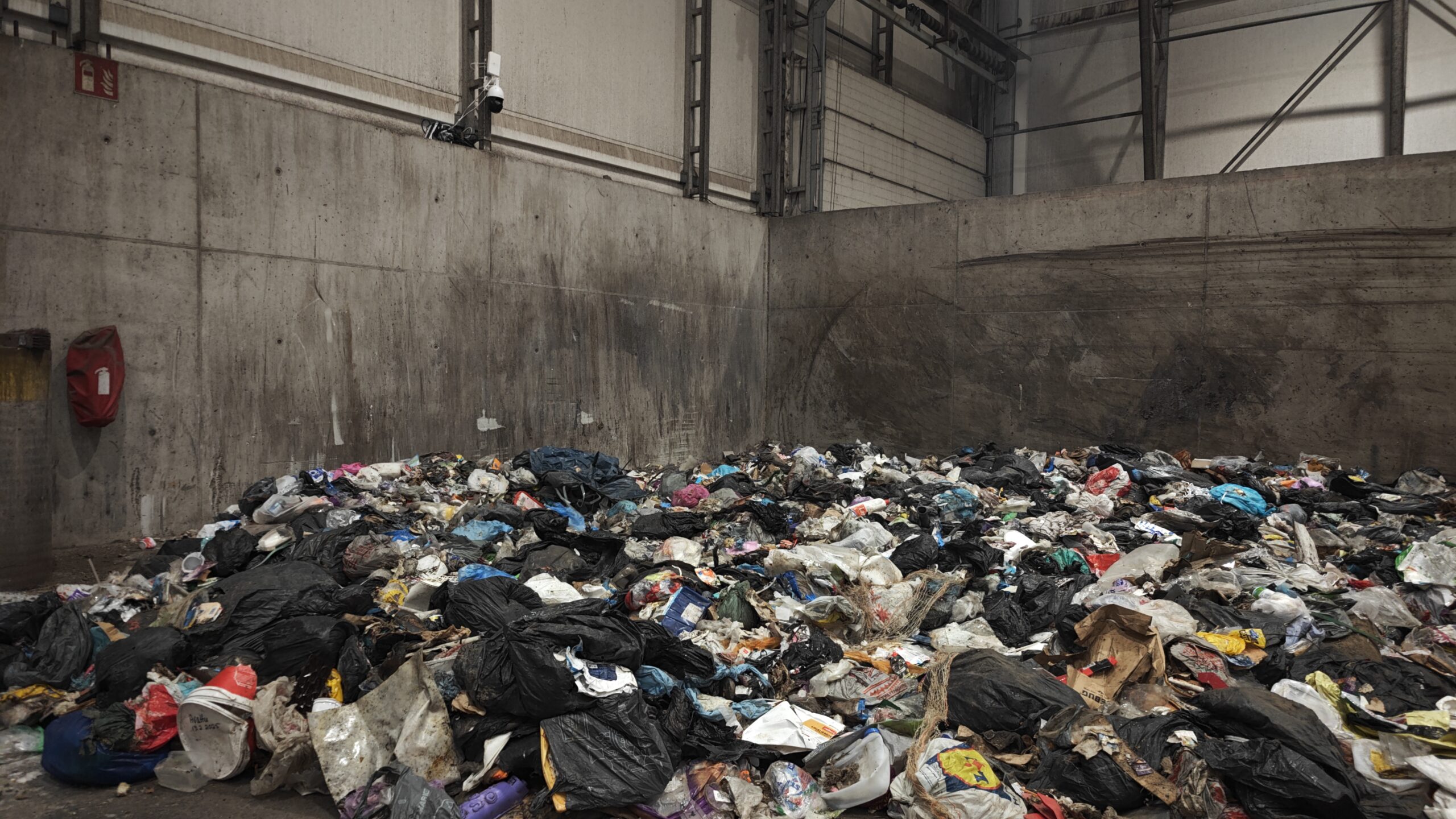 Jätteitä tunnistava kameralaitteisto asennettuna jätekasan viereen varastohallissa